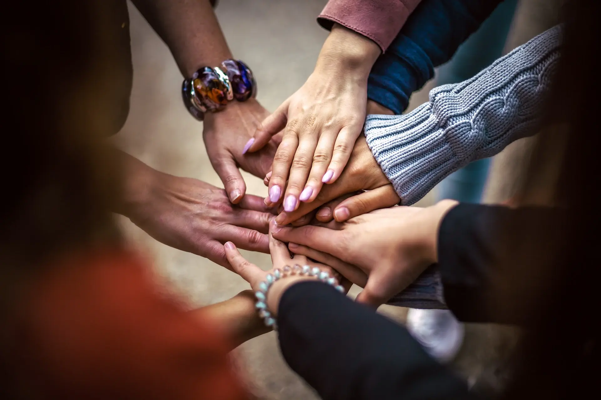 Many hands of different skin tones stacked together in a circle