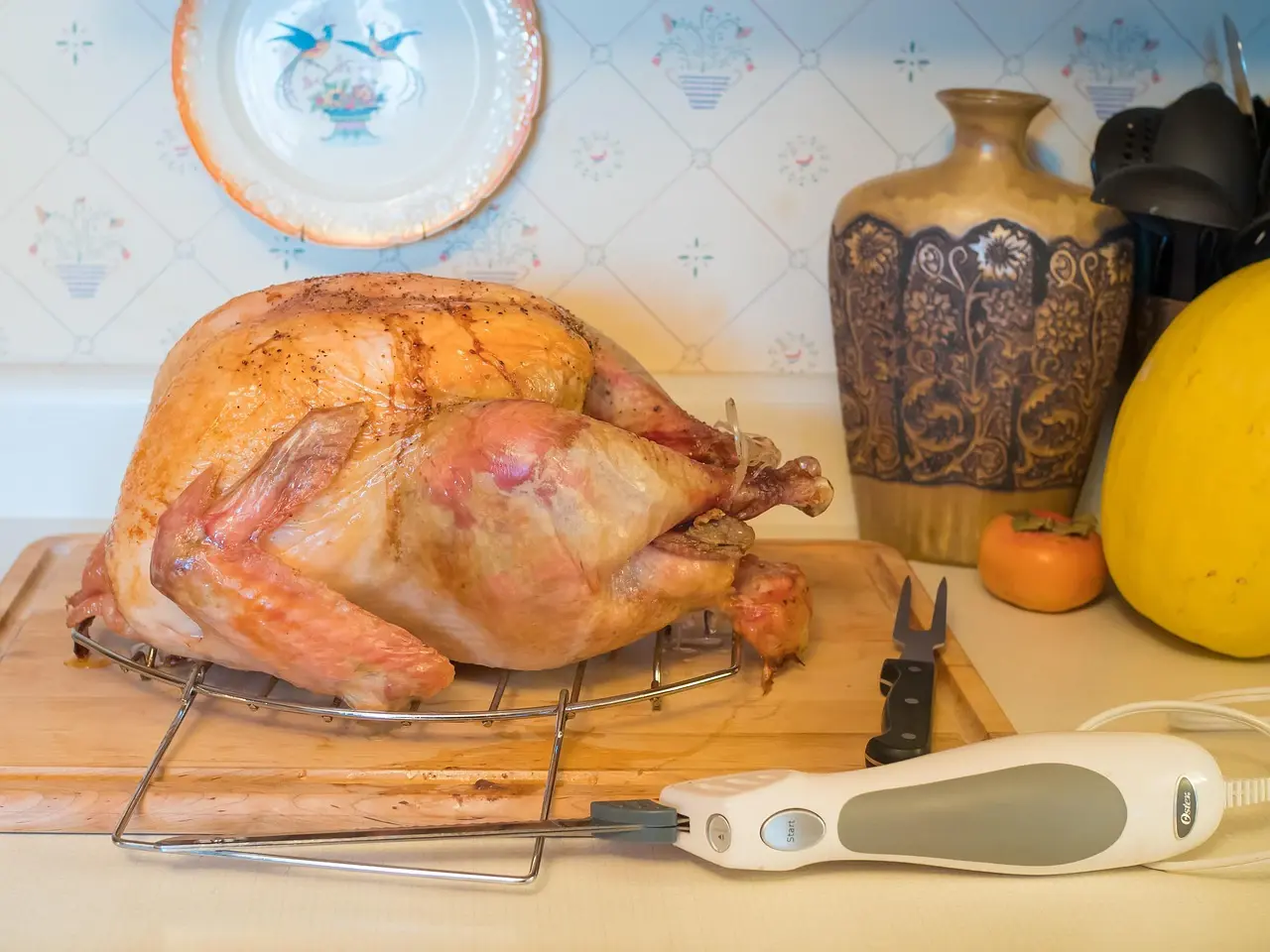 A roast turkey on a carving board with a Thanksgiving table setting